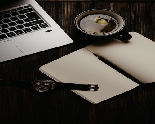 A notebook and a cup of tea on a wooden table, representing morning planning